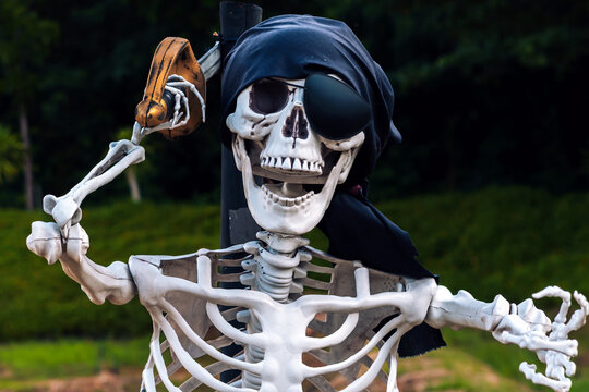 Human pirate skeleton prop wear black eye patch and headscarf, holding sword. Concept for Halloween outdoor decorations, pirate theme party props, haunted house attractions, and seasonal holiday.