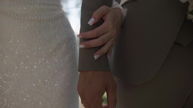 Close up of newlywed couple holding hands on their wedding day