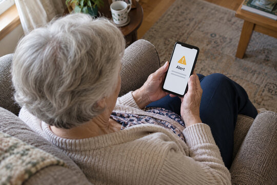 Senior woman reading a security alert on her smartphone at home