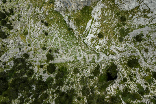 Aerial Limestone Karst Landscape with Cave Entrance and Winding Mountain Trail