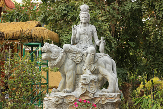 Wide view landscape banner of stone Guanyin statue riding sacred lion mount, horizontal garden backdrop with oriental sculptures exhibition