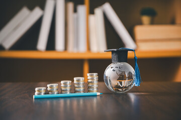 Graduation globe stands beside rising stacks of coins and a pencil, representing education investment, tuition growth, student savings, financial planning, scholarship funding, and future goals. © Manasanan Wongchoomp