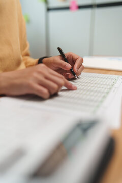 Close-up of a Female professional reviewing an accounting spreadsheet and financial document with a pen, auditor, expense tracking, analysis and business records and tax form.