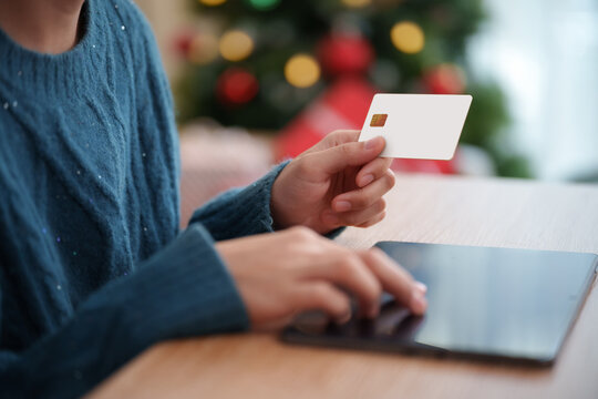 Woman holding credit card while shopping online on digital tablet during Christmas and New Year, digital payment, e-commerce checkout, seasonal discounts and festive retail sales.