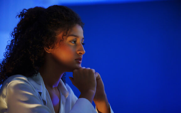 Focused cybersecurity Female analyst monitoring in a dark blue workspace, representing data security, threat detection, network protection, privacy, risk analysis and cyber defense.