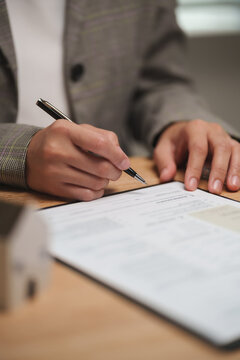 Close-up of a mortgage officer signing and reviewing a home loan application, representing property finance, contract approval, mortgage processing and home purchase.