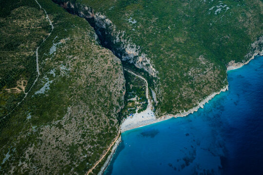Gjipe Beach secluded beach destination in a dramatic coastal gorge beside turquoise sea and rugged vegetated cliffs