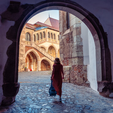 Woman tourist entering the historic courtyard through an arch at Corvin Castle in Hunedoara Romania