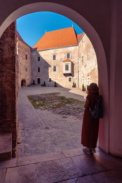 Woman tourist looking into the sunlit courtyard of Corvin Castle in Hunedoara Transylvania Romania