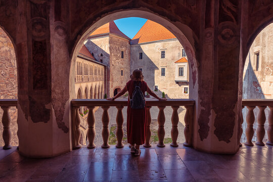 Woman tourist overlooking the courtyard from an arched gallery at Corvin Castle in Hunedoara Romania