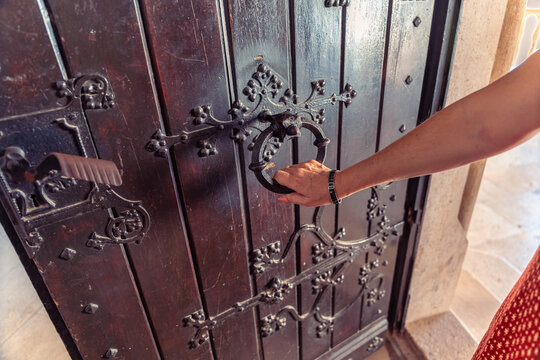 Woman touching an ornate iron door knocker inside Corvin Castle in Hunedoara Transylvania Romania