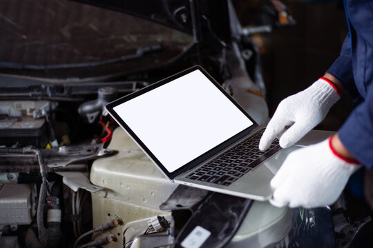 Male mechanic connecting laptop to car engine system for diagnostic test