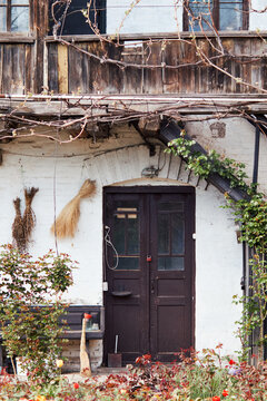 Rustic house entrance with weathered wooden facade, vintage door, vines and garden