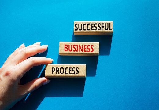  Concept words successful business process on wooden blocks arranged as steps. Businessman hand arranging wooden blocks. Business development concept. Blue background. Copy space.