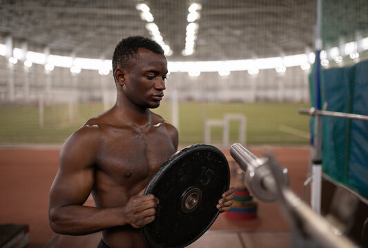 Muscular black athlete preparing barbell during workout