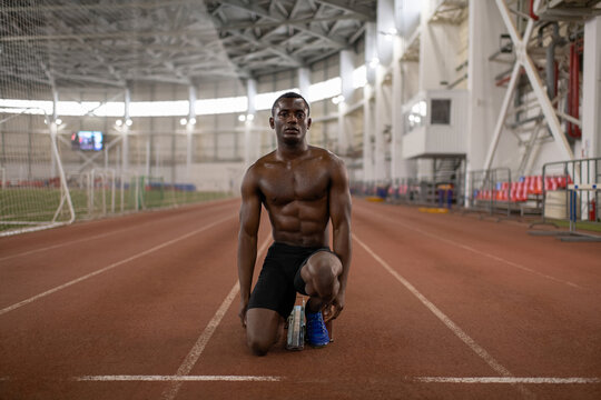 Strong black runner kneeling on track during training