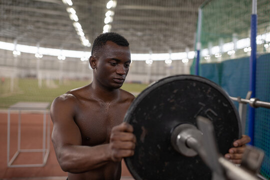 Black athlete attaching weight to bar