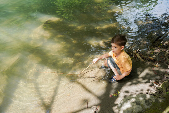 The Child Spends Time In Nature Near The Water In A Calm