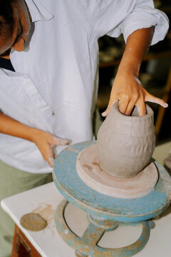 Person Shapes a Clay Pot on a Pottery Wheel in the Studio