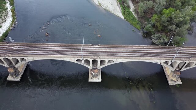 Milan &ndash; Pavia &ndash; Genoa railway line: drone view of a regional train and an Intercity train crossing the bridge over the Ticino River in Pavia, Italian Railways and the modernization of the rail network