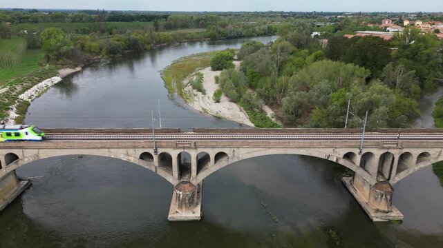 Milan &ndash; Pavia &ndash; Genoa railway line: drone view of a regional train and an Intercity train crossing the bridge over the Ticino River in Pavia, Italian Railways and the modernization of the rail network