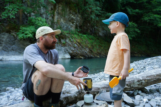 Father And Son Are Making Tea By The River In Nature