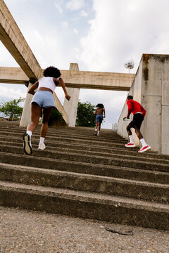 Low-angle shot of runner friends climbing park stairs.