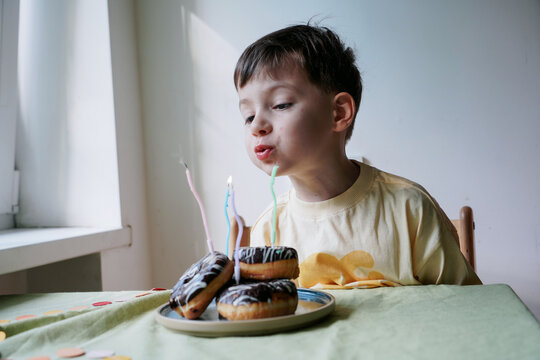 A Boy Blows Out Candles At A Birthday Party