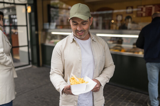 Customer with takeaway Belgian fries at street food stall