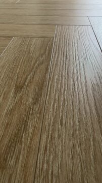 Vertical 4K video showing a static extreme low angle macro shot of natural oak floor texture with detailed wood grain. Highlights the classic herringbone parquet pattern and subtle sheen.