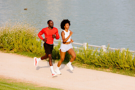 Full-body shot of elite runners training in a park.
