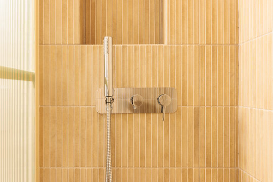 Chrome shower fixture on beige tiles