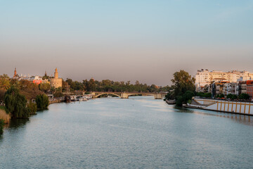 Obraz premium Colorful riverside buildings along the Guadalquivir River in Seville at dusk