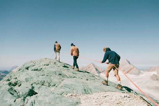 Hikers climbing a steep rocky ridge in single file, connected by a vibrant safety rope for adventure travel and teamwork campaigns, with copy space