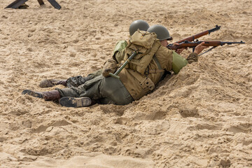 Obraz premium Historical reconstruction. An American infantry soldiers from the World War II fight on the beach. 