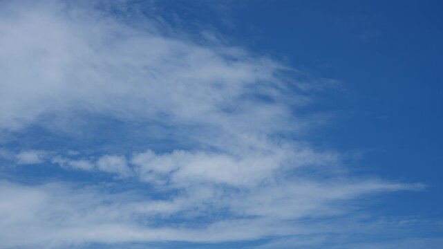 A blue sky cloud timelapse video featuring wispy cirrus and layered stratocumulus clouds drifting across a sunlit sky, capturing natural daylight, changing weather, and a calm atmospheric scene. 4k.
