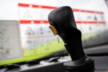 Control joystick lever with forward neutral reverse switch inside modern agricultural tractor or construction vehicle cabin. © Marina