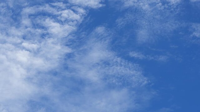 A blue sky cloud timelapse video featuring patchy altocumulus and cirrocumulus clouds drifting in sunlight, capturing natural weather patterns, airy atmosphere, and a calm daytime sky.
