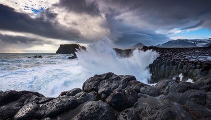 Fototapeta premium sea foam crashing against black lava rocks under a dramatic sky in iceland