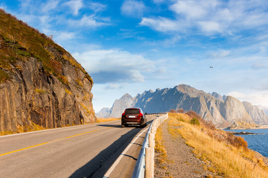 A car driving on a coastal mountain road at autumn