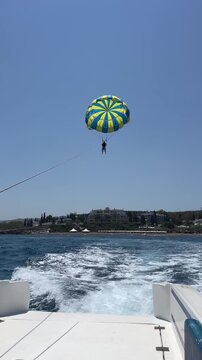 Two people parasailing in the blue sky over the sea, view from the boat