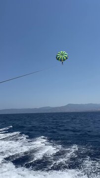 Two people parasailing in the blue sky over the sea, view from the boat