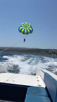Two people parasailing in the blue sky over the sea, view from the boat