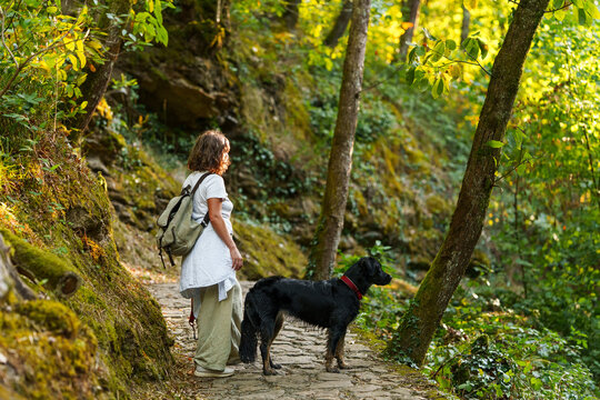 Woman walking with her black dog in an autumn forest