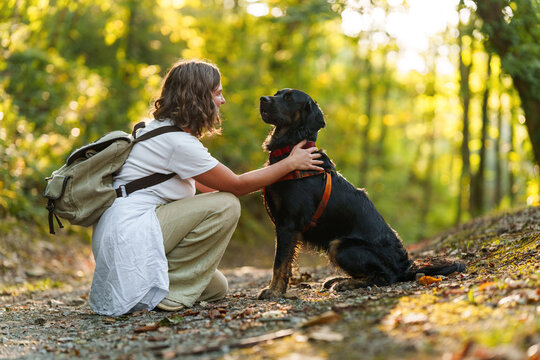 Woman walking with her black dog in an autumn forest