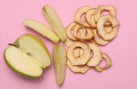 Ripe apples and apple chips on a pastel background