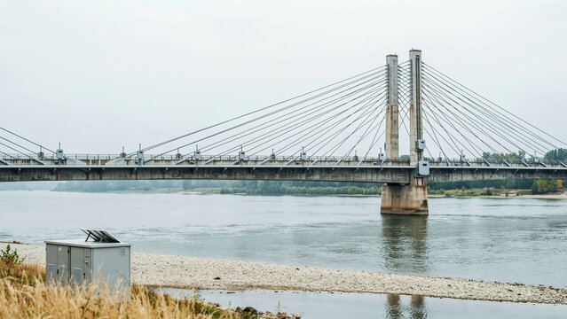 Modern cable-stayed bridge spanning across a wide river with concrete pillars, steel cables, and industrial engineering infrastructure