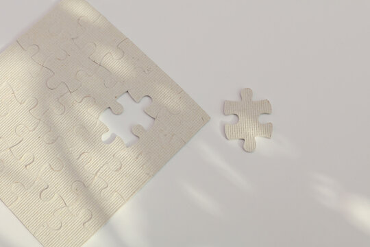 White puzzle pieces against a background of shadows from leaves, sunlight