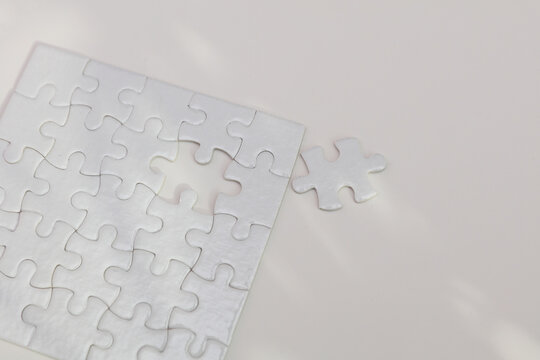White puzzle pieces against a background of shadows from leaves, sunlight