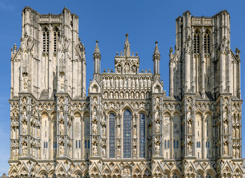 Detaillierte Au&szlig;enansicht der historischen gotischen Westfassade der Kathedrale von Wells mit mittelalterlichen Skulpturen unter blauem Himmel in Somerset, England.